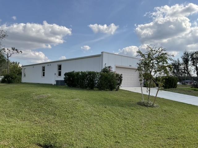 view of side of home featuring cooling unit, a garage, and a lawn