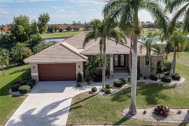4077 La Costa Island Ct, Punta Gorda, FL 33950 - view of front of house featuring an attached garage, a front lawn, stucco siding, a water view, and french doors