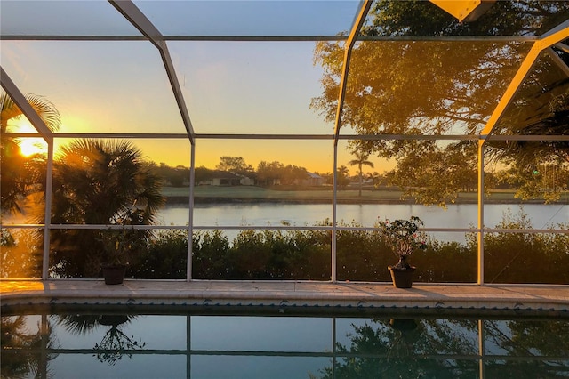 pool at dusk with a water view and glass enclosure