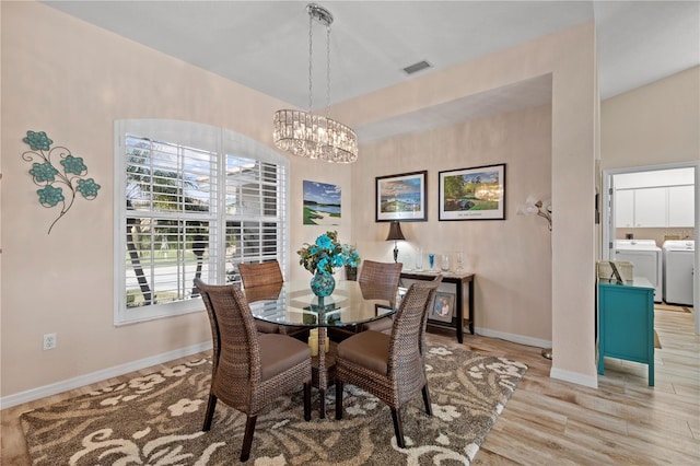 dining area featuring light hardwood / wood-style floors, a notable chandelier, and washing machine and clothes dryer