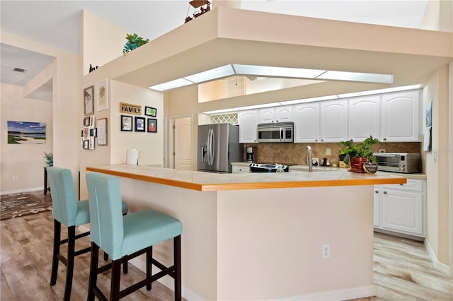 kitchen with tile countertops, appliances with stainless steel finishes, and white cabinetry