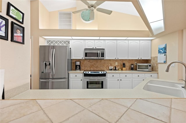 kitchen featuring decorative backsplash, white cabinets, stainless steel appliances, and sink