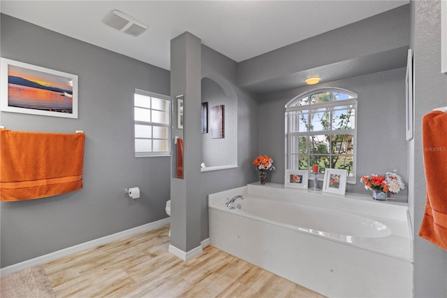 4077 La Costa Island Ct, Punta Gorda, FL 33950 - bathroom with visible vents, a garden tub, wood finished floors, toilet, and baseboards