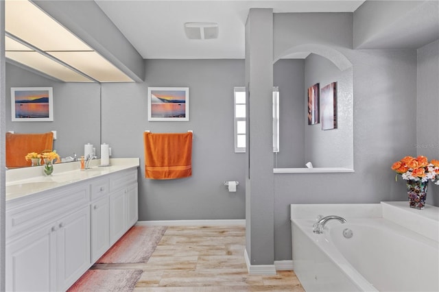 4077 La Costa Island Ct, Punta Gorda, FL 33950 - bathroom with a garden tub, baseboards, wood finished floors, and vanity