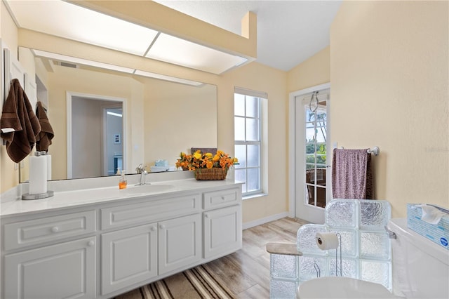 bathroom with vanity, vaulted ceiling, hardwood / wood-style flooring, and toilet