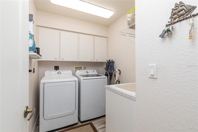 washroom with independent washer and dryer, light hardwood / wood-style floors, and cabinets