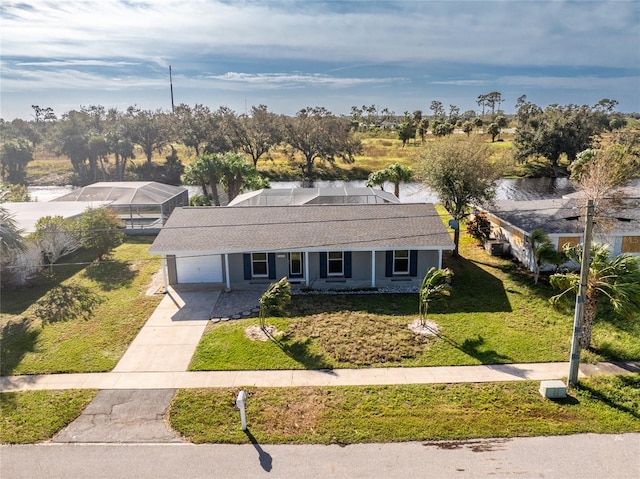 single story home with a front lawn, covered porch, a garage, and a water view