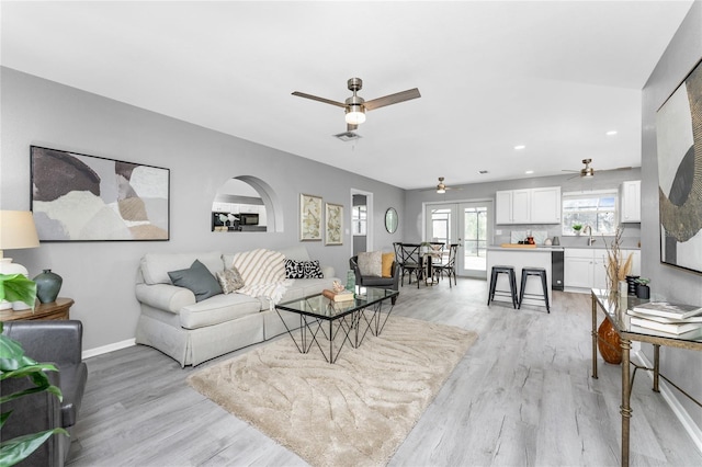 living room with french doors, ceiling fan, and light wood-type flooring