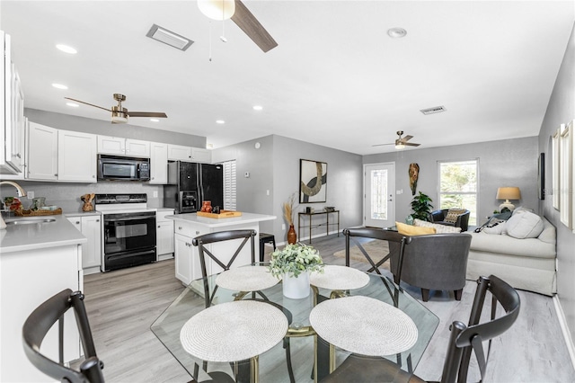 dining space with ceiling fan, sink, and light wood-type flooring