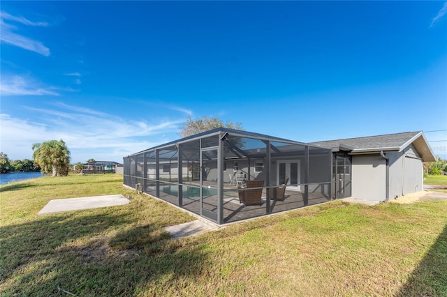 back of house with a yard, a patio area, a lanai, and a water view