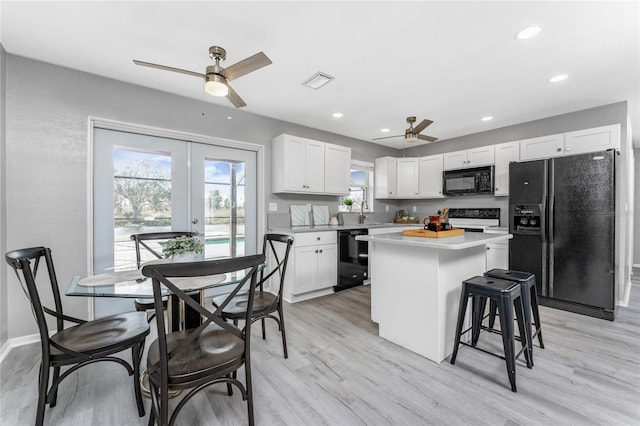 kitchen featuring black appliances, white cabinetry, and light hardwood / wood-style flooring