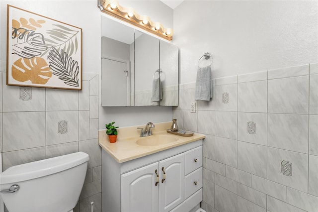 bathroom with vanity, toilet, and tile walls