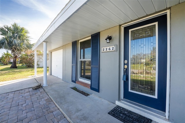 doorway to property with covered porch and a garage