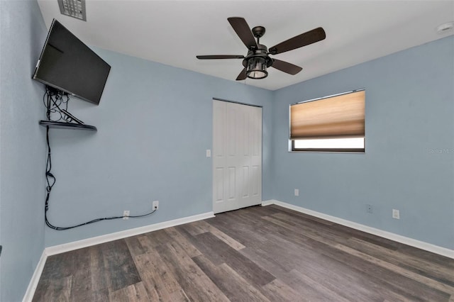 unfurnished bedroom with a closet, ceiling fan, and dark hardwood / wood-style flooring