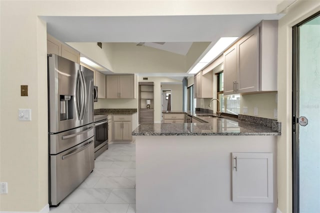 kitchen with sink, kitchen peninsula, stainless steel appliances, lofted ceiling, and dark stone countertops