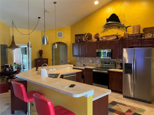 kitchen featuring sink, a kitchen bar, stainless steel appliances, light tile patterned floors, and a center island with sink