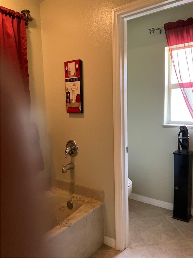 bathroom with a tub, toilet, and tile patterned flooring