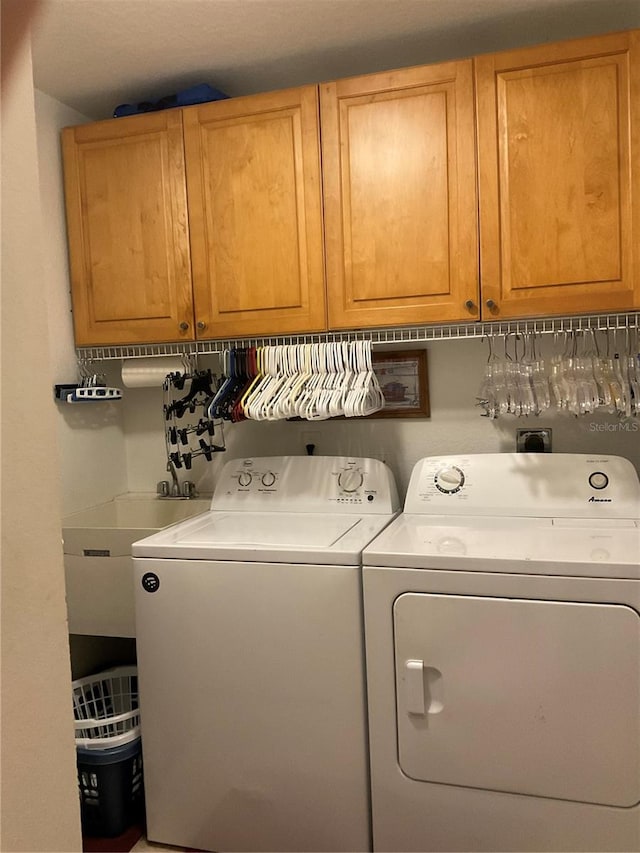 clothes washing area featuring washer and dryer and cabinets