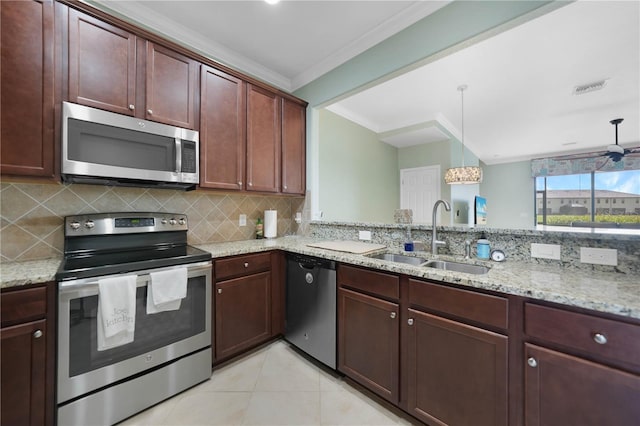 kitchen featuring hanging light fixtures, sink, appliances with stainless steel finishes, tasteful backsplash, and light stone counters