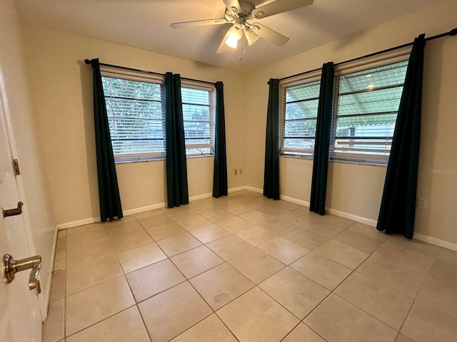 tiled empty room featuring ceiling fan and plenty of natural light