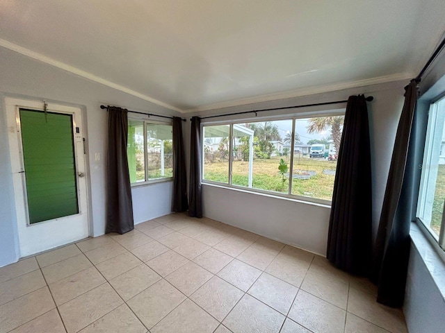 tiled spare room with vaulted ceiling, ornamental molding, and plenty of natural light