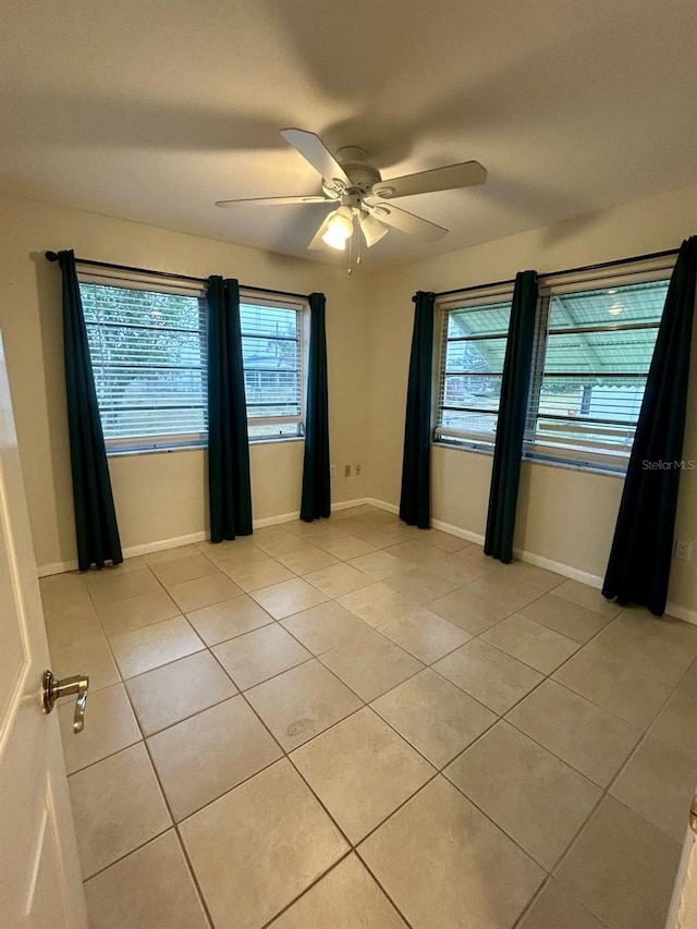 empty room with ceiling fan and light tile patterned floors