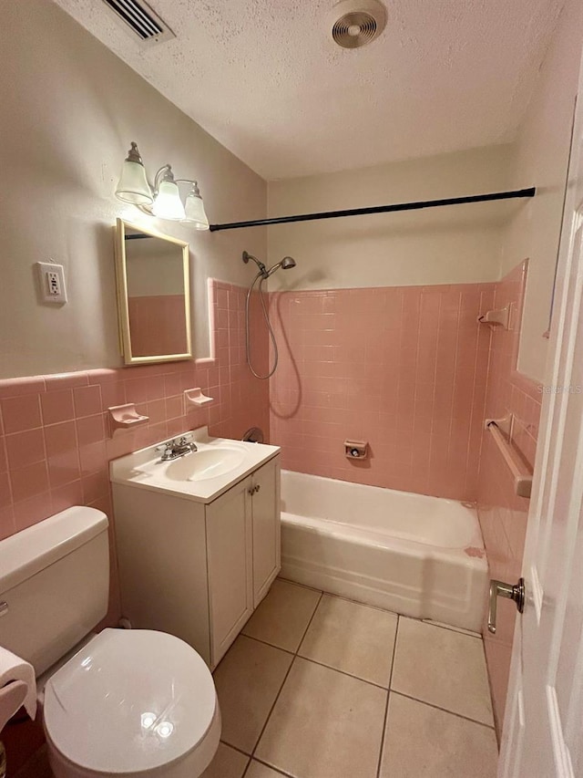 full bathroom with tiled shower / bath, tile patterned flooring, vanity, tile walls, and toilet