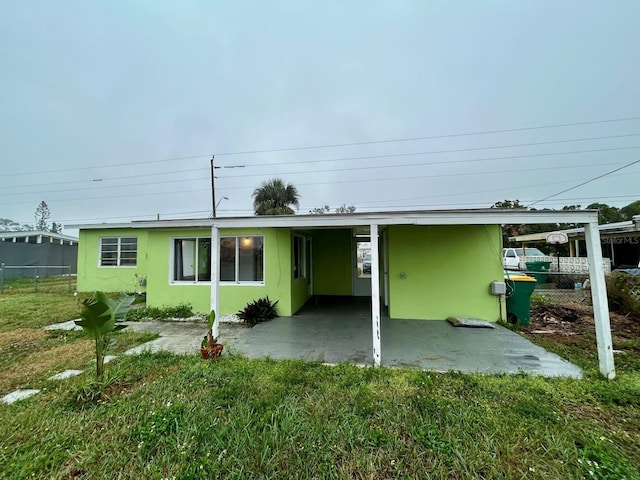 rear view of house featuring a carport and a lawn