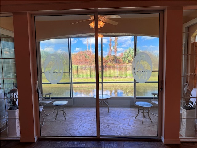 entryway with ceiling fan, a water view, and a wealth of natural light