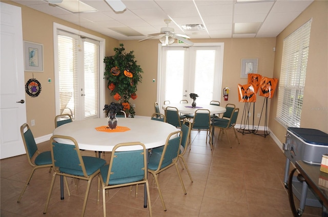 tiled dining area with french doors, a drop ceiling, and ceiling fan