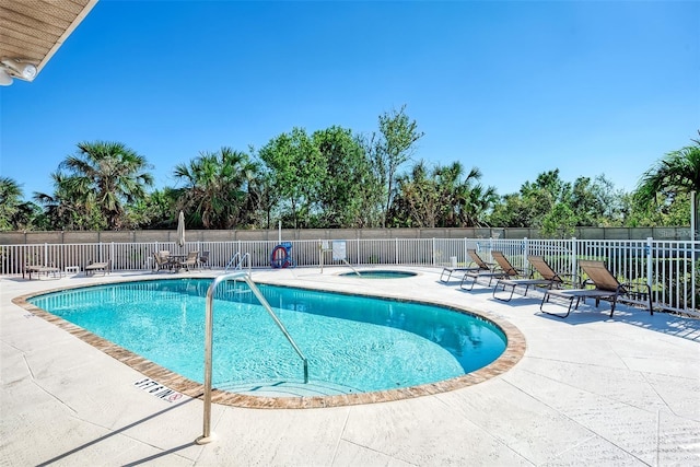 view of swimming pool with a hot tub and a patio