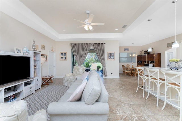 living room with ceiling fan with notable chandelier and a raised ceiling