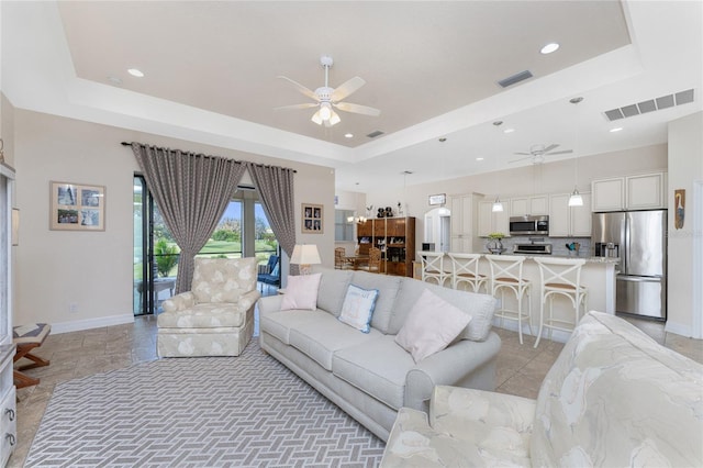 living room featuring a tray ceiling and ceiling fan