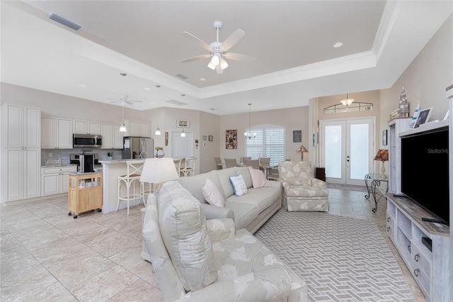 living room featuring ornamental molding, french doors, a tray ceiling, and ceiling fan with notable chandelier