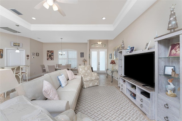 living room with french doors, crown molding, ceiling fan with notable chandelier, and a raised ceiling