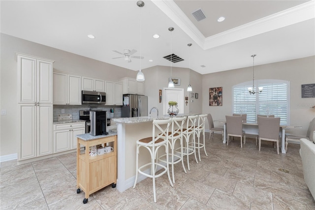 kitchen with white cabinets, tasteful backsplash, appliances with stainless steel finishes, a kitchen island with sink, and light stone counters