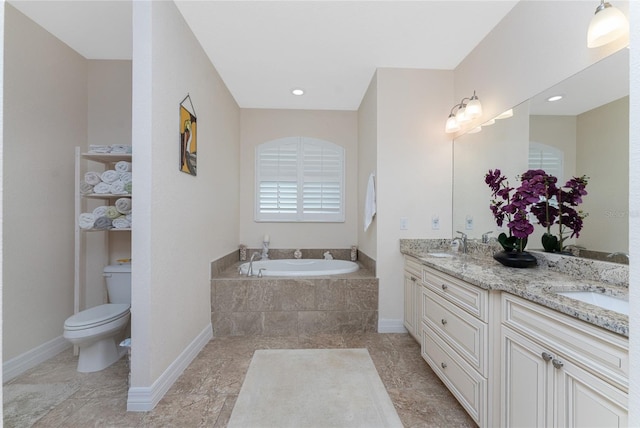 bathroom with vanity, toilet, and tiled tub