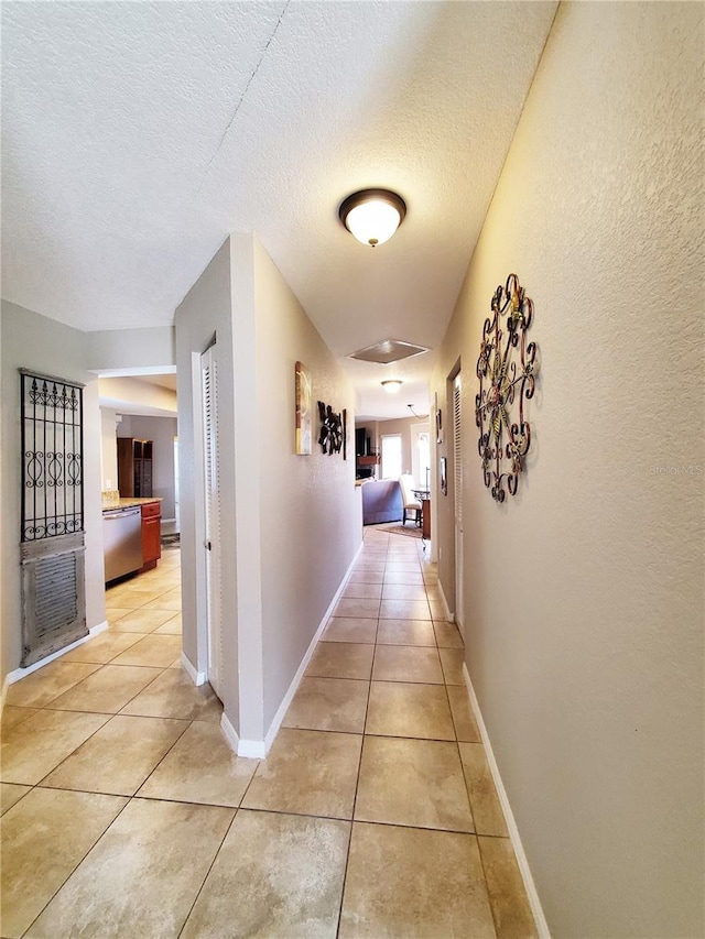 corridor with a textured ceiling and light tile patterned floors