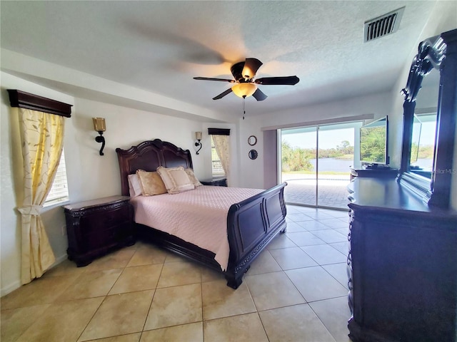 tiled bedroom with ceiling fan, a textured ceiling, and access to exterior