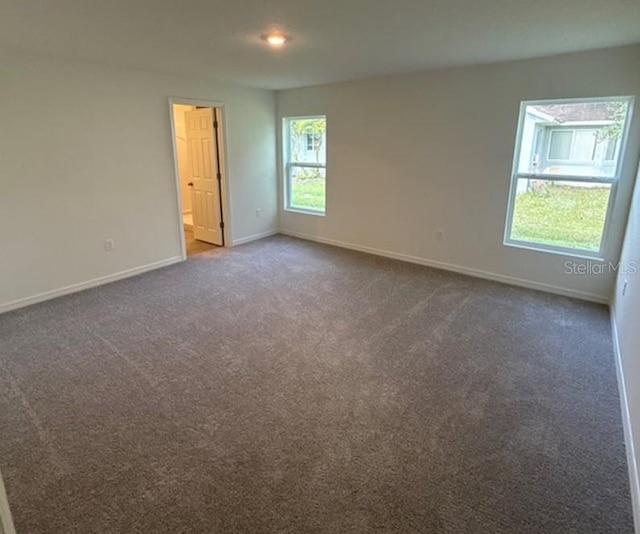 unfurnished room with dark colored carpet