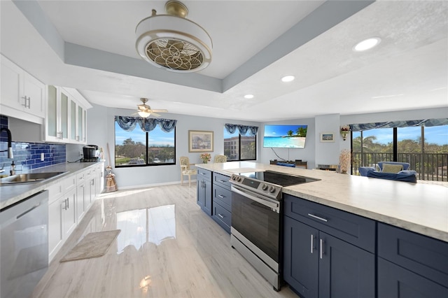 kitchen with appliances with stainless steel finishes, decorative backsplash, white cabinets, and a healthy amount of sunlight