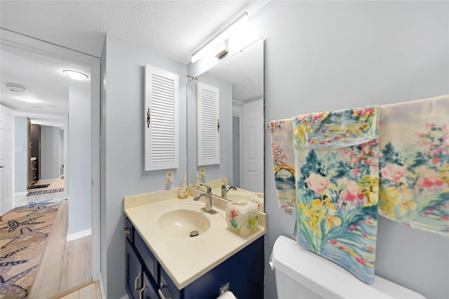 bathroom featuring toilet, a textured ceiling, hardwood / wood-style flooring, and vanity