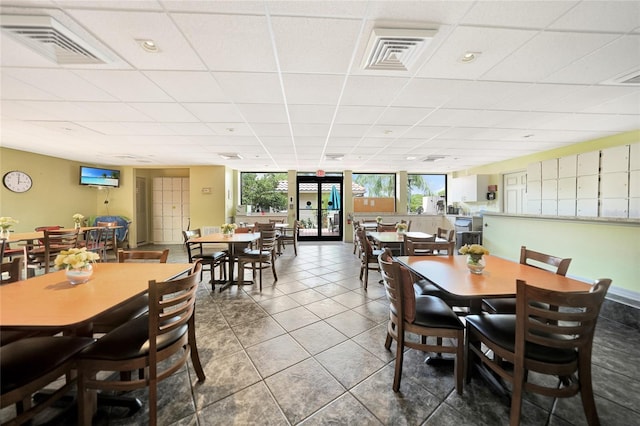 dining area with a paneled ceiling and tile patterned floors