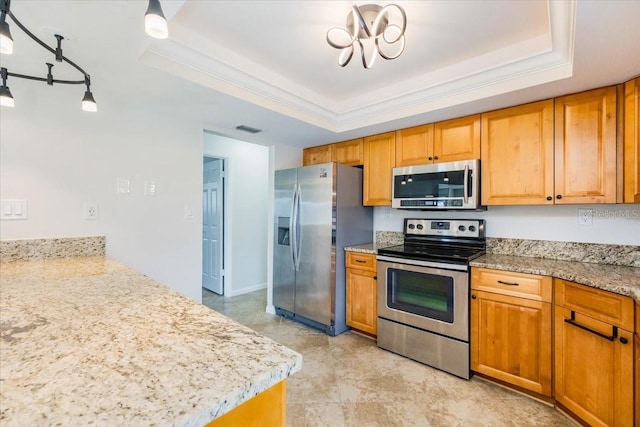 kitchen with pendant lighting, appliances with stainless steel finishes, and a tray ceiling