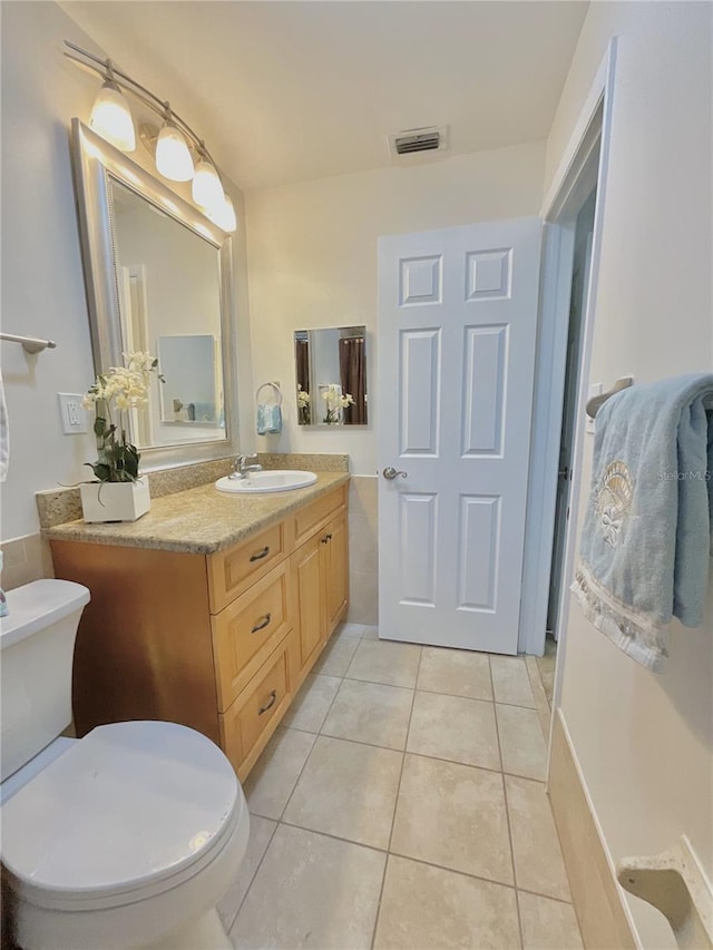 bathroom with toilet, vanity, and tile patterned floors