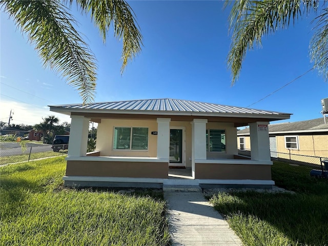 view of front of home with cooling unit, a front lawn, and covered porch