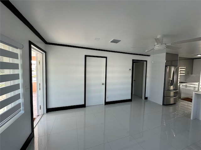 empty room featuring light tile patterned floors, ceiling fan, and crown molding