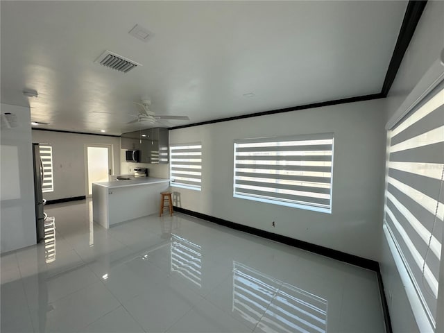 empty room with ceiling fan, plenty of natural light, light tile patterned flooring, and ornamental molding