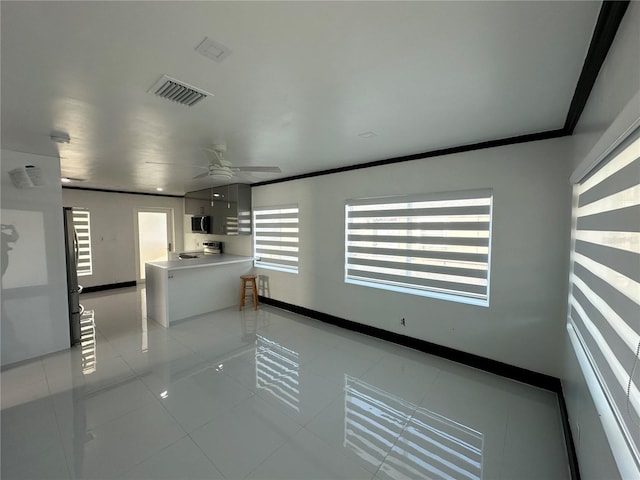 spare room with light tile patterned floors, a wealth of natural light, ceiling fan, and ornamental molding