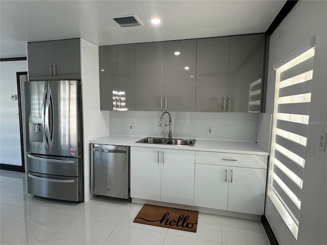 kitchen featuring appliances with stainless steel finishes, light tile patterned floors, gray cabinetry, and sink